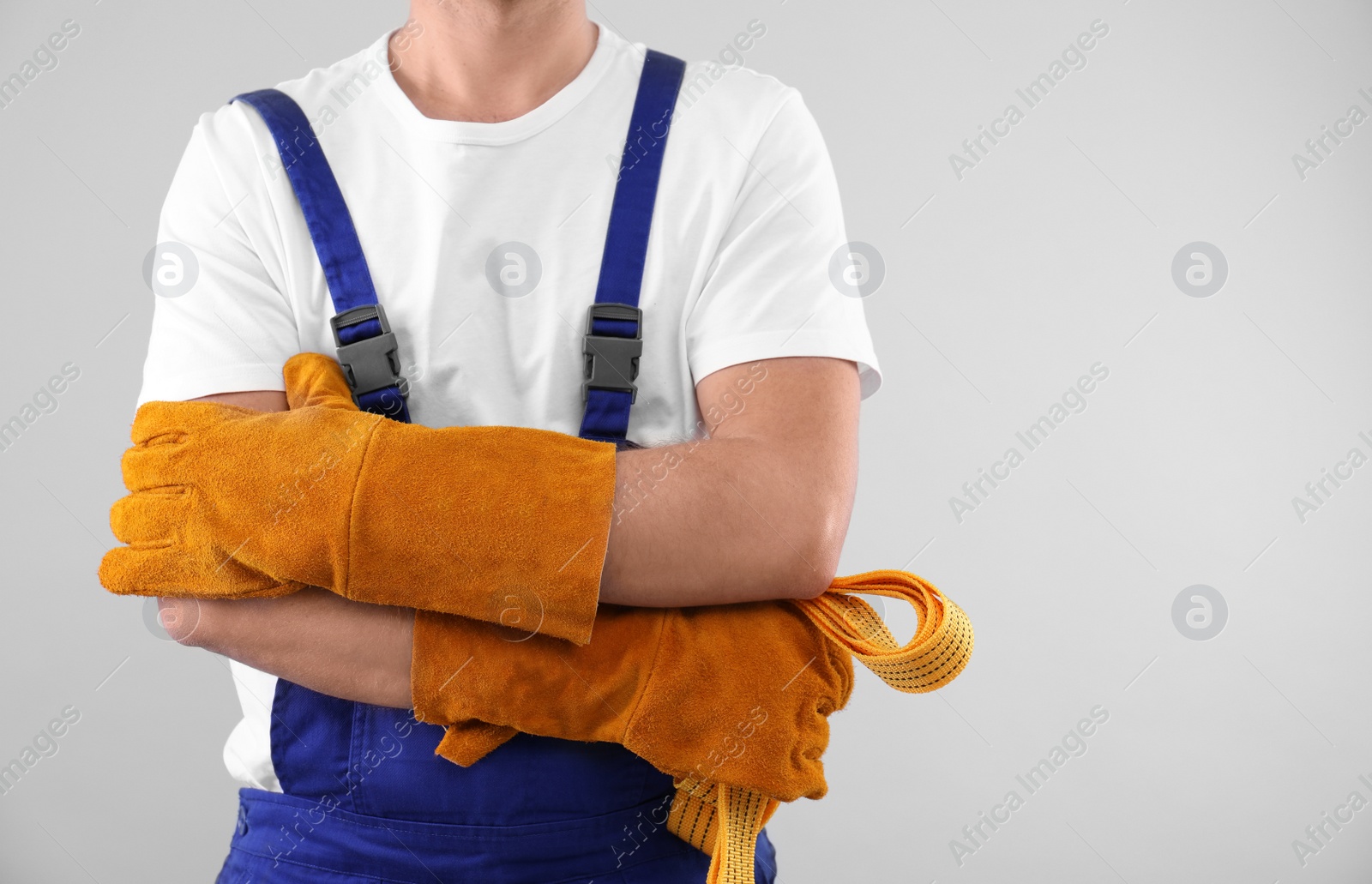 Photo of Male industrial worker in uniform on light background, closeup with space for text. Safety equipment