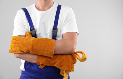 Male industrial worker in uniform on light background, closeup with space for text. Safety equipment