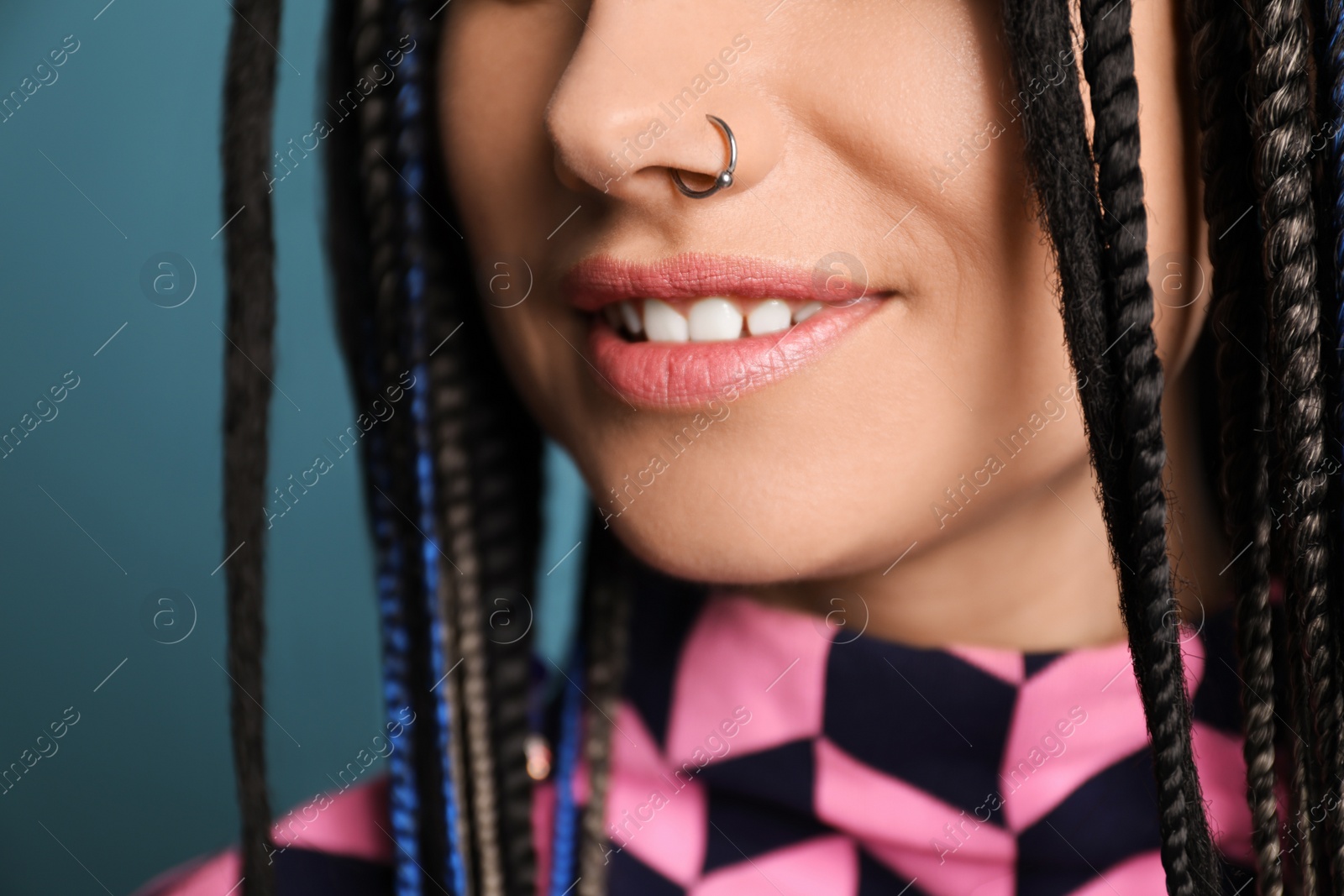 Photo of Young woman with nose piercing on light blue background, closeup