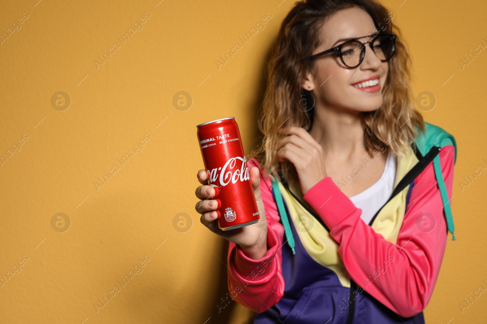 Photo of MYKOLAIV, UKRAINE - NOVEMBER 28, 2018: Young woman with Coca-Cola can on color background, space for text