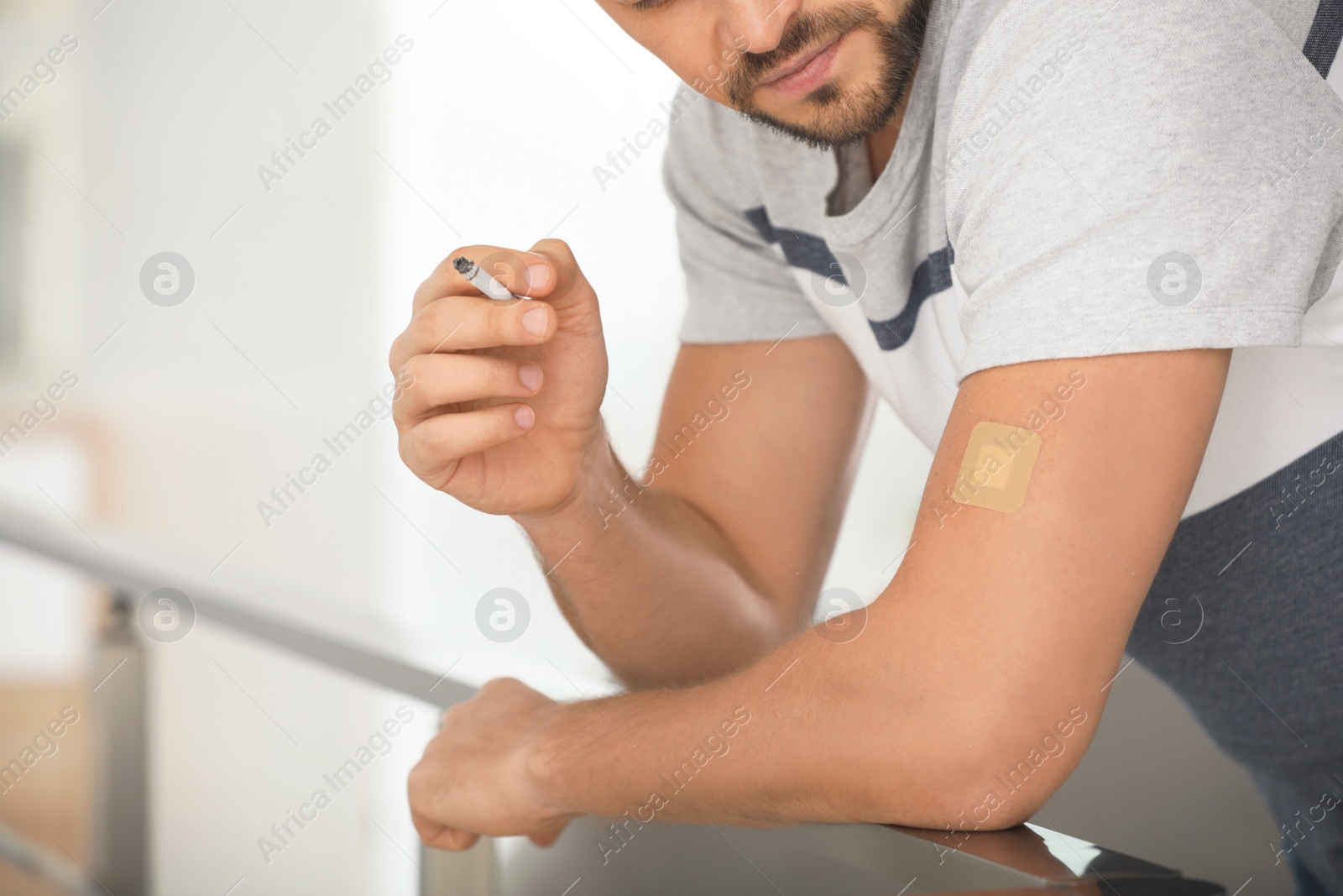 Photo of Man with nicotine patch and cigarette indoors, closeup