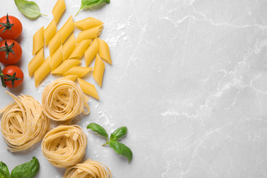 Flat lay composition with different types of pasta on light grey table. Space for text