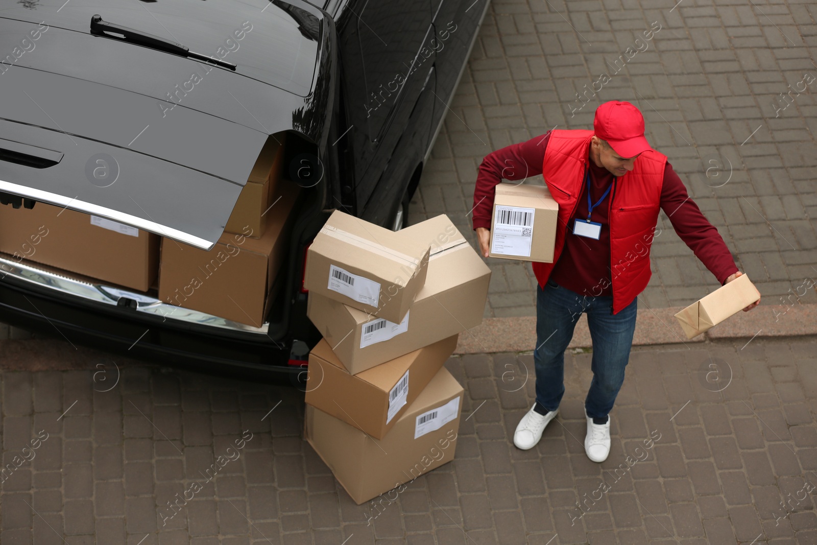 Photo of Courier with parcels near delivery van outdoors, above view