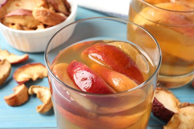 Delicious compot with dried apple slices on light blue table, closeup