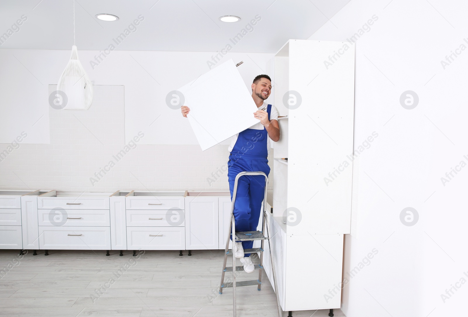 Photo of Worker installing door of cabinet in kitchen