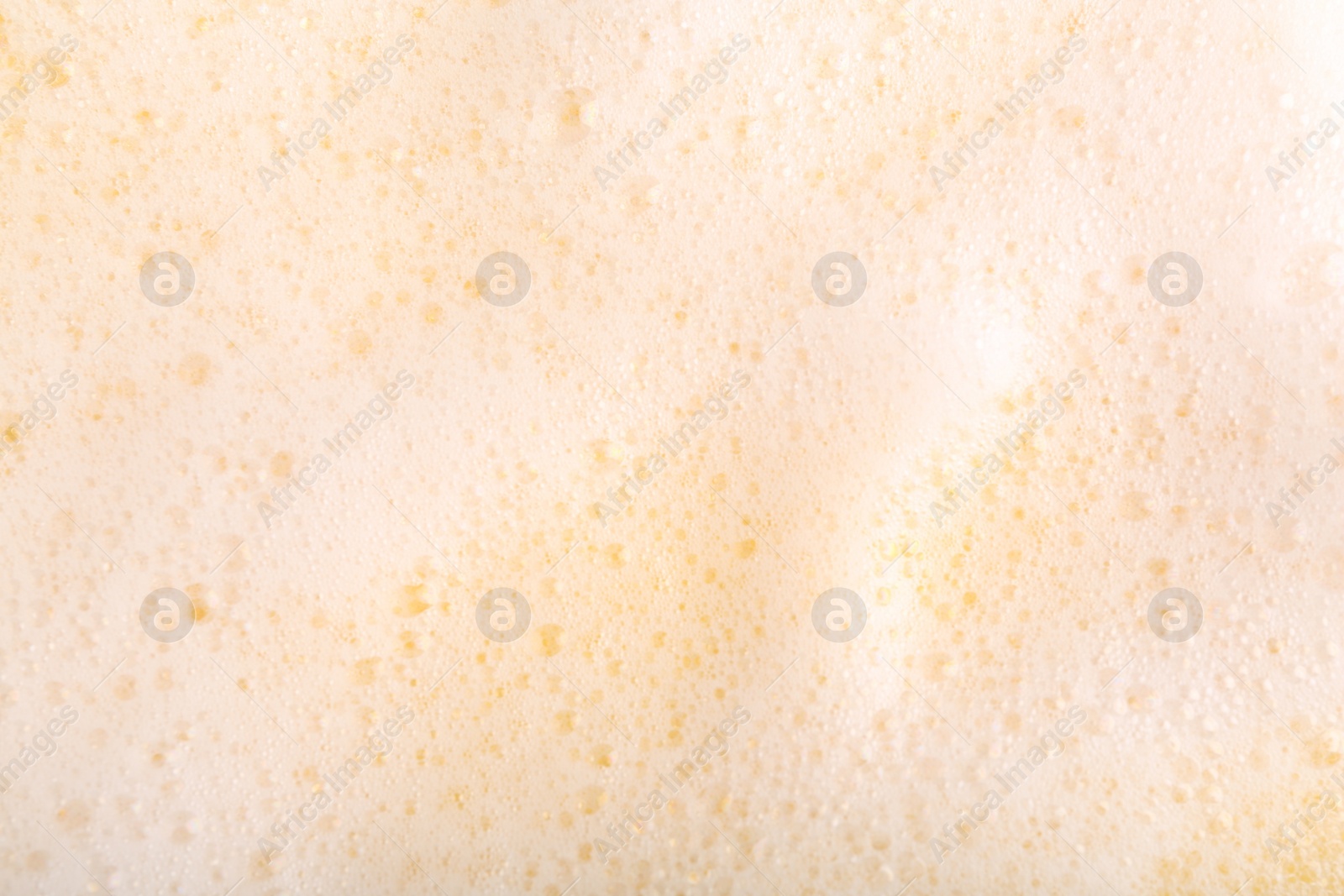 Photo of White fluffy foam on yellow background, top view