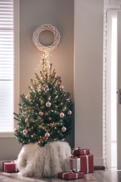 Christmas tree and gift boxes near window in room. Festive interior design