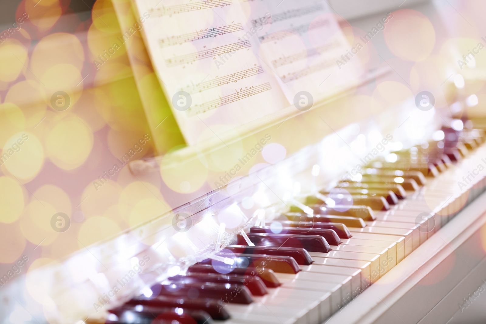 Image of Christmas and New Year music. Piano with fairy lights, bokeh effect