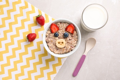 Photo of Tasty porridge served with berries and milk on marble table, flat lay. Creative idea for kids breakfast