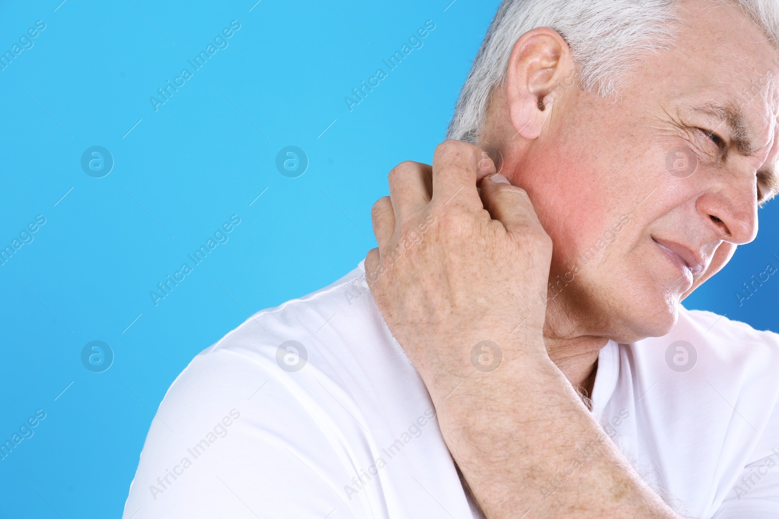 Photo of Senior man scratching neck on color background, closeup with space for text. Allergy symptom