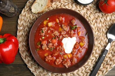 Photo of Bowl of delicious stuffed pepper soup served on wooden table, flat lay