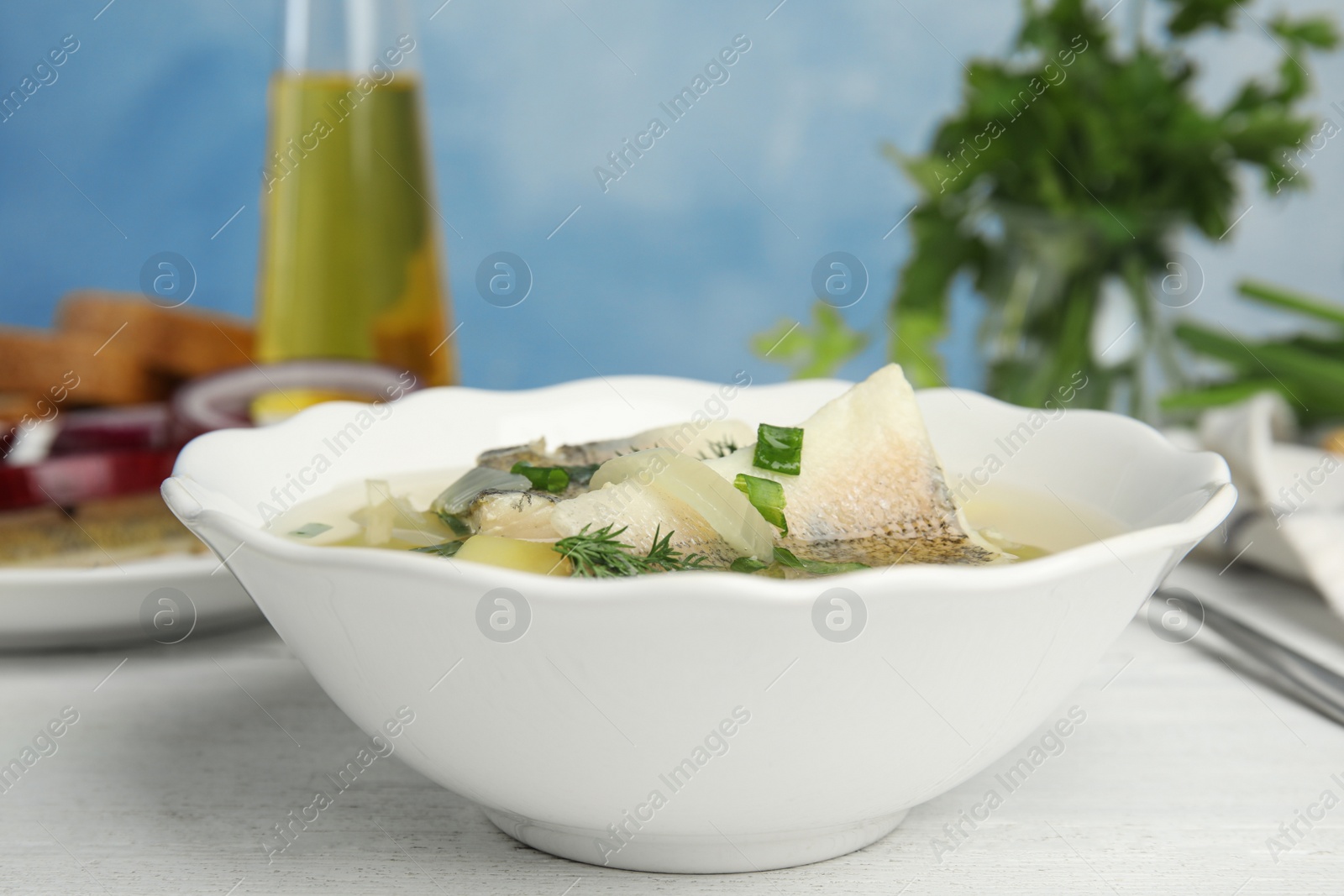 Photo of Delicious fish soup in bowl on white wooden table