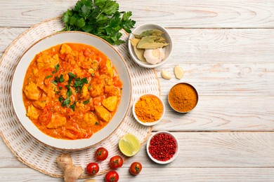 Photo of Delicious chicken curry and ingredients on wooden table, flat lay. Space for text