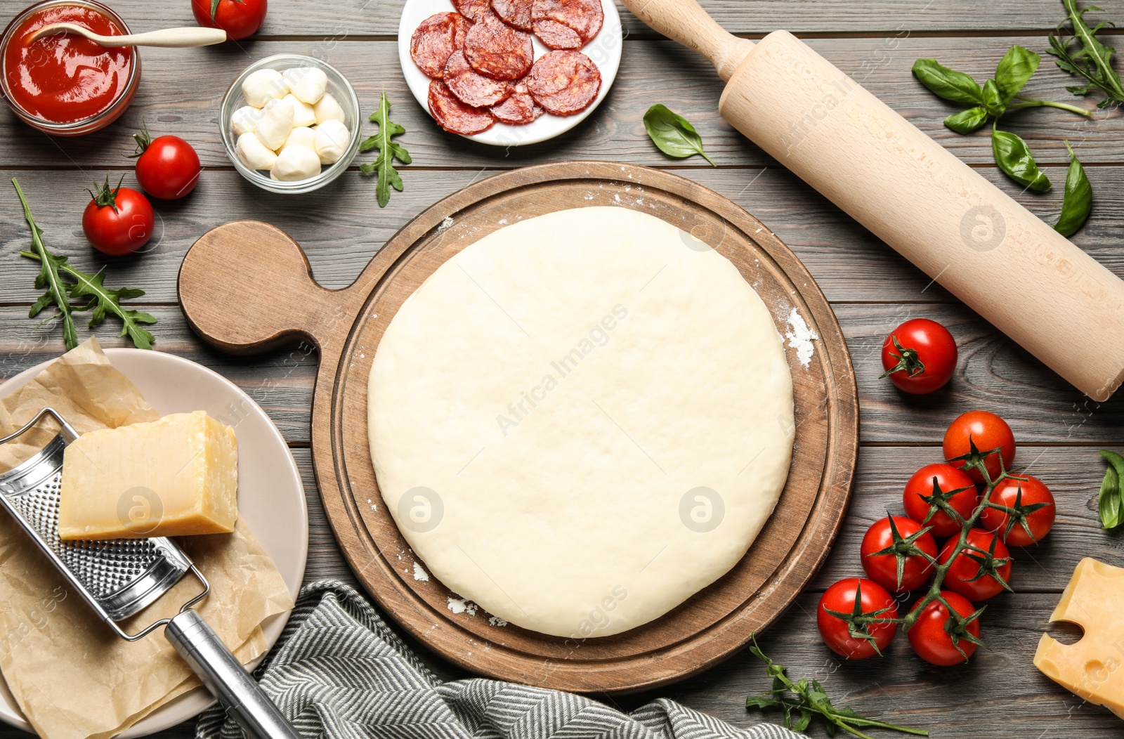 Photo of Flat lay composition with dough and fresh ingredients for pepperoni pizza on wooden table