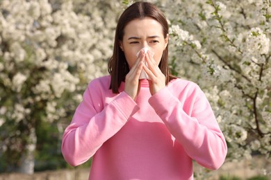 Woman with napkin suffering from seasonal allergy on spring day