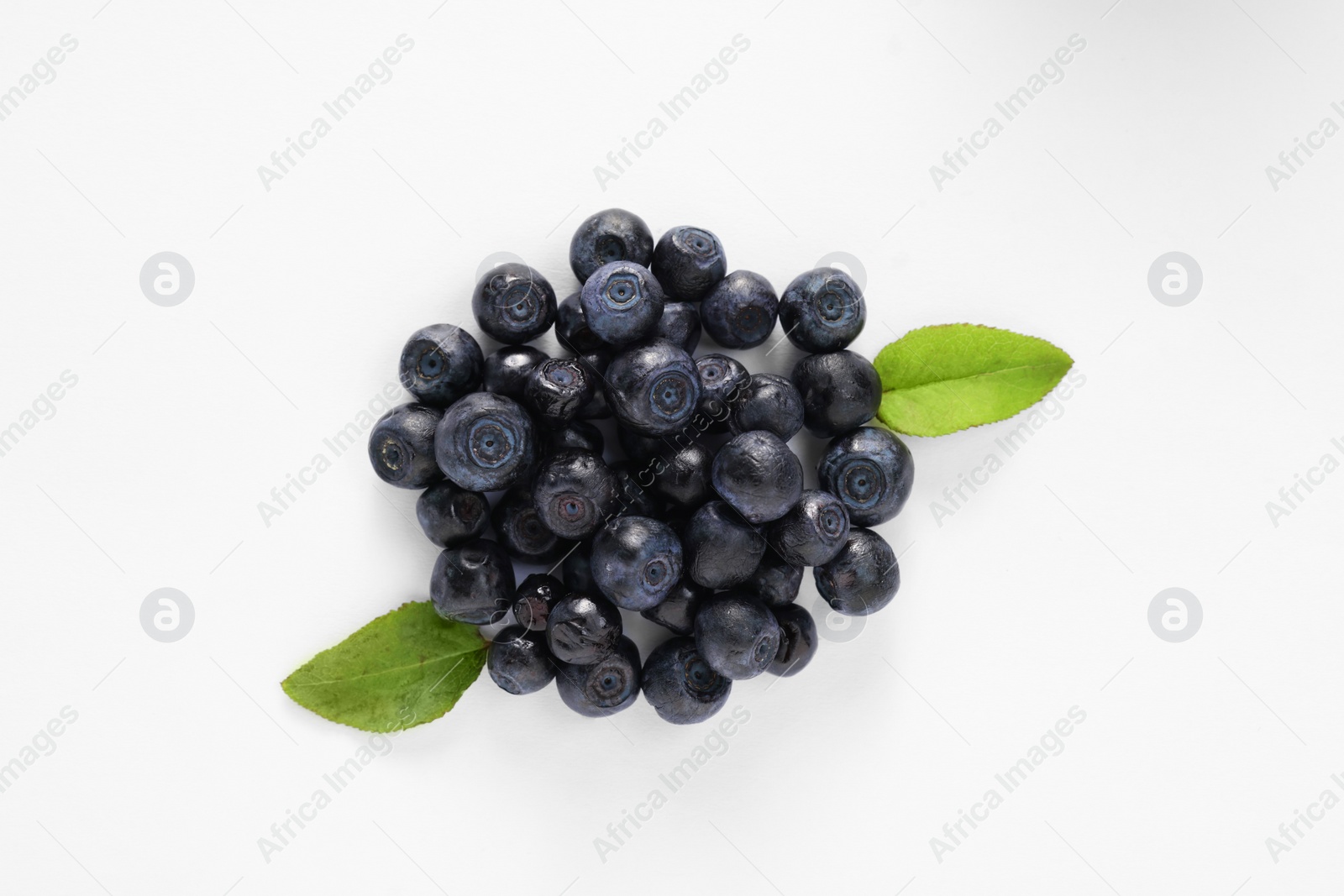 Photo of Pile of ripe bilberries and leaves on white background, flat lay