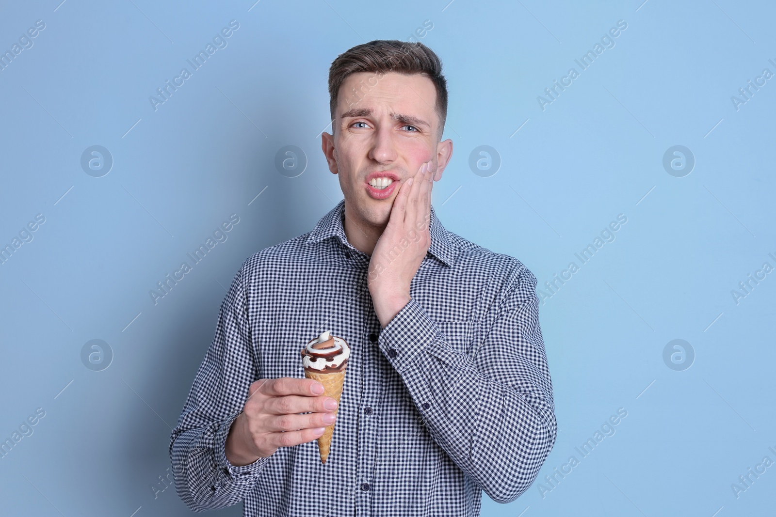 Photo of Young man with sensitive teeth and cold ice cream on color background