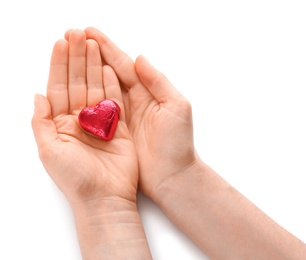 Photo of Woman holding heart shaped chocolate candy on white background, top view