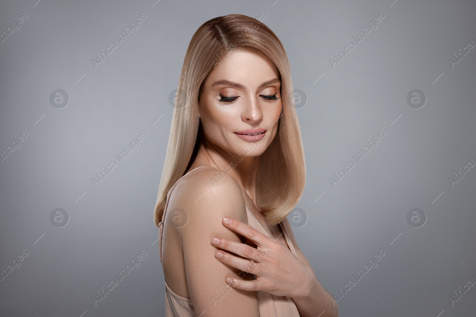 Image of Portrait of attractive woman with blonde hair on grey background