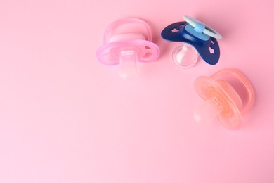 Photo of Colorful baby pacifiers on pink background, flat lay. Space for text