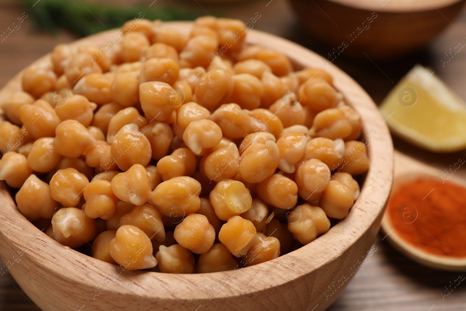 Photo of Delicious chickpeas on wooden table, closeup. Hummus ingredient