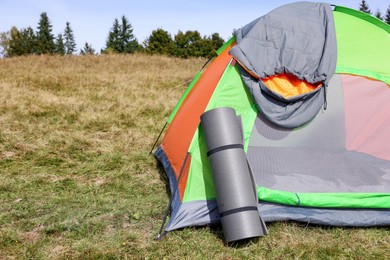 Photo of Grey sleeping bag on camping tent and mat outdoors, space for text