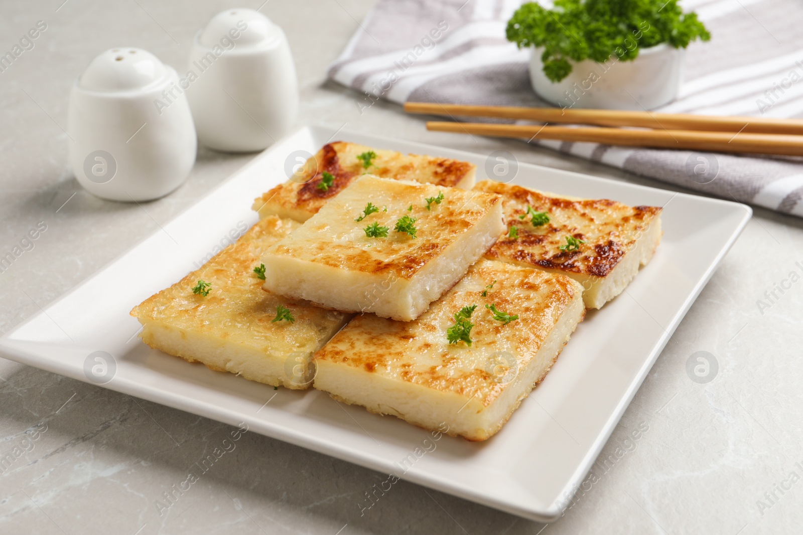 Photo of Delicious turnip cake with parsley served on light table