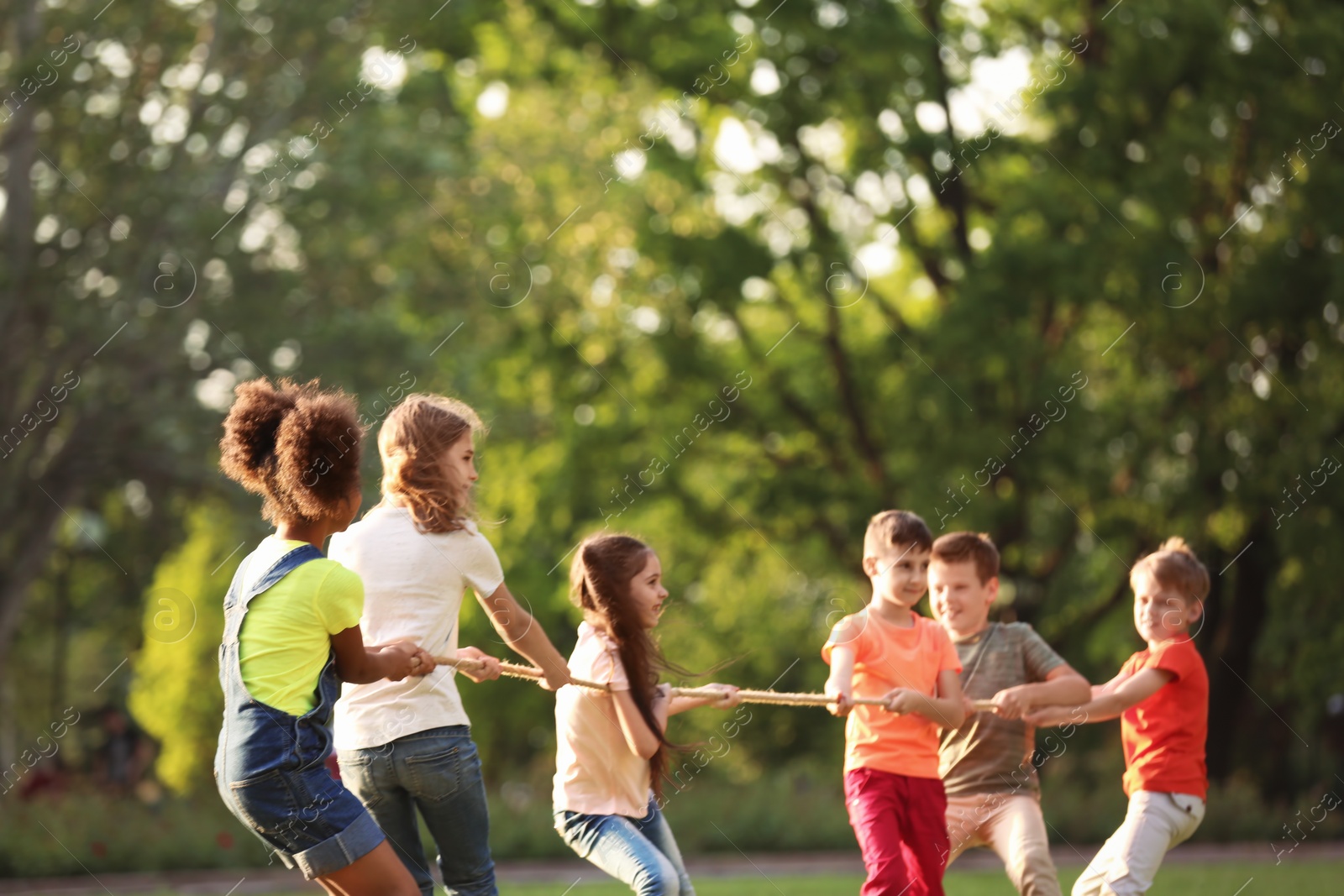 Photo of Cute little children playing with rope outdoors on sunny day