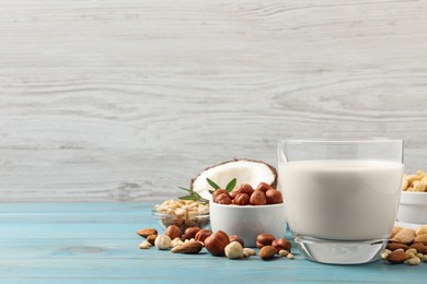 Photo of Vegan milk and different nuts on light blue wooden table. Space for text