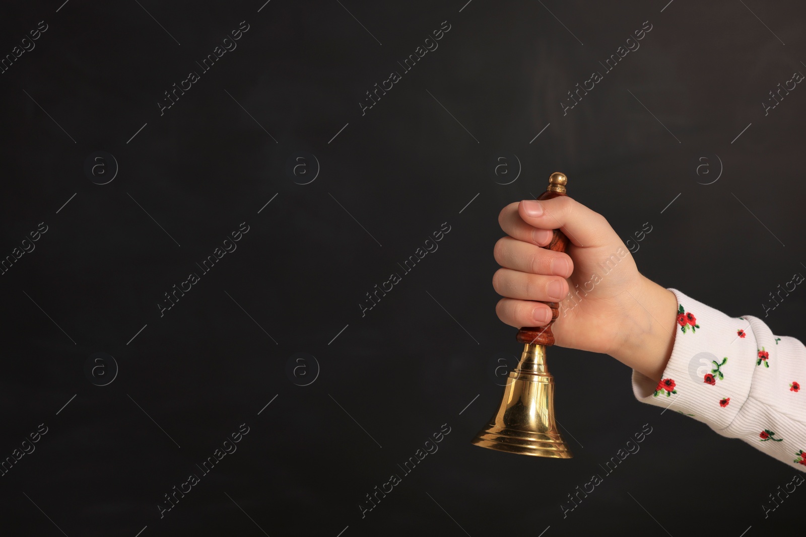 Photo of Pupil with school bell near black chalkboard, closeup. Space for text