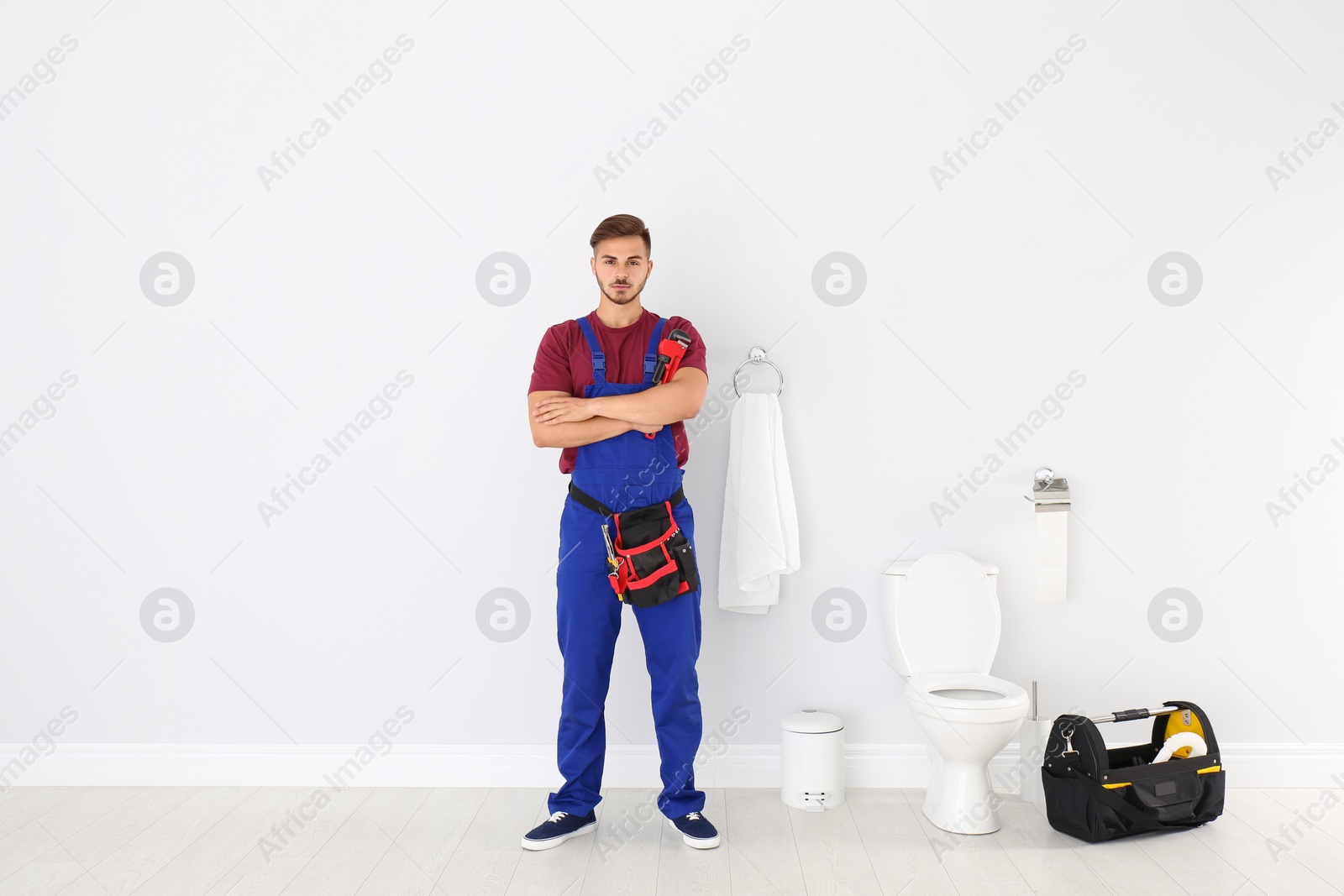 Photo of Young man with plumber wrench near toilet bowl in bathroom