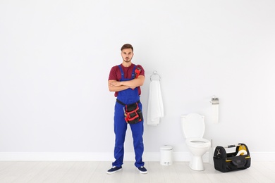 Young man with plumber wrench near toilet bowl in bathroom