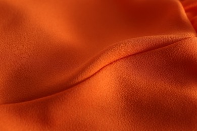 Texture of orange crumpled fabric as background, closeup view