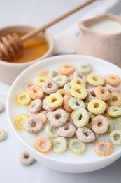 Photo of Cereal rings and milk in bowl on white table, closeup