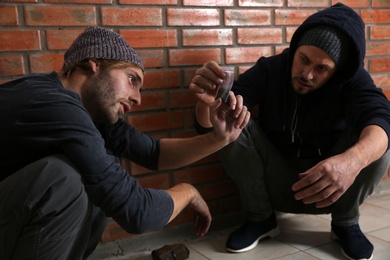 Young addicted men with hemp near brick wall