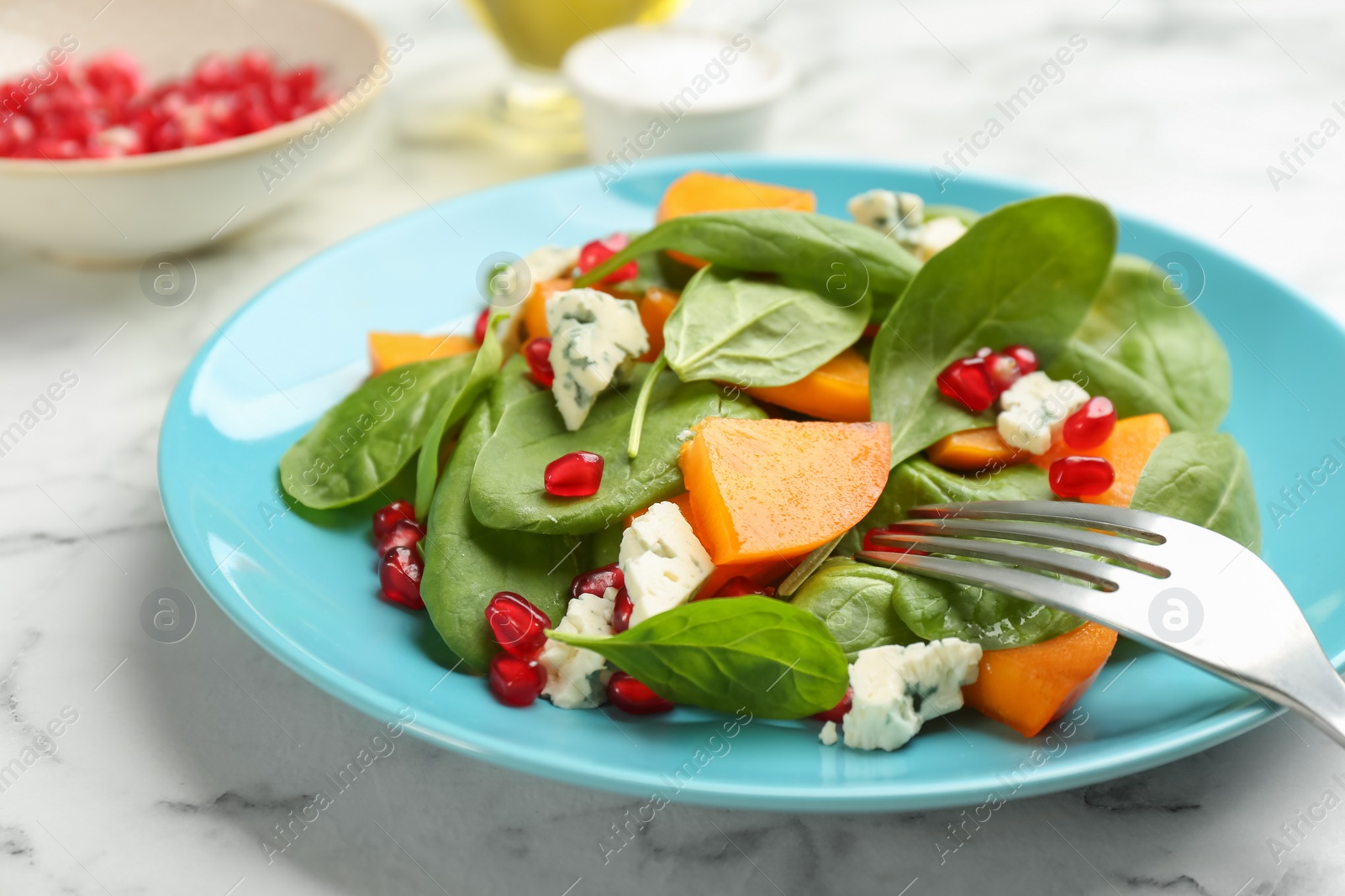 Photo of Delicious persimmon salad served on white marble table, closeup