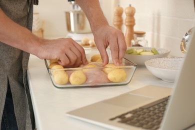 Man making dinner while watching online cooking course via laptop in kitchen, closeup