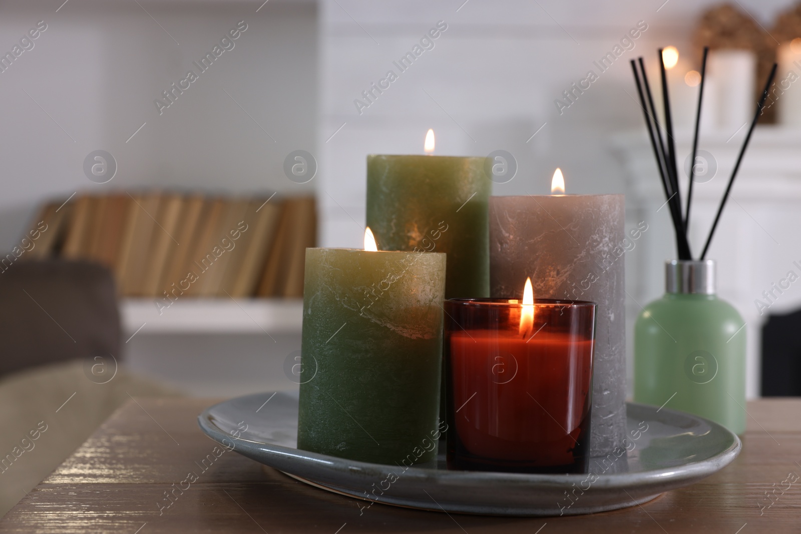 Photo of Beautiful burning candles and air freshener on wooden table indoors, space for text