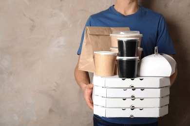 Photo of Courier with stack of orders on beige background, space for text. Food delivery service