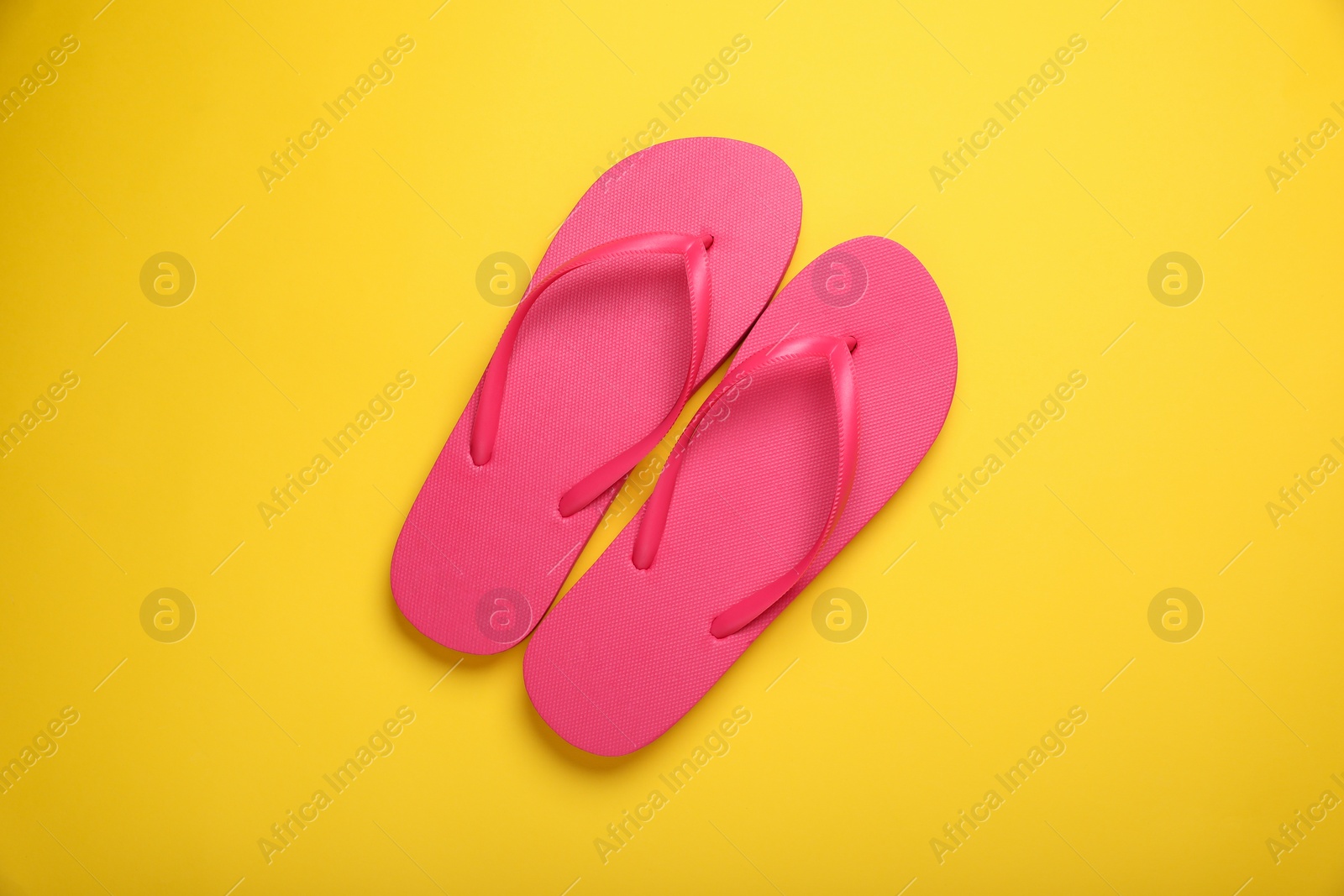 Photo of Stylish pink flip flops on yellow background, top view