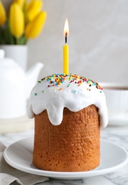 Photo of Beautiful Easter cake with candle on white marble table