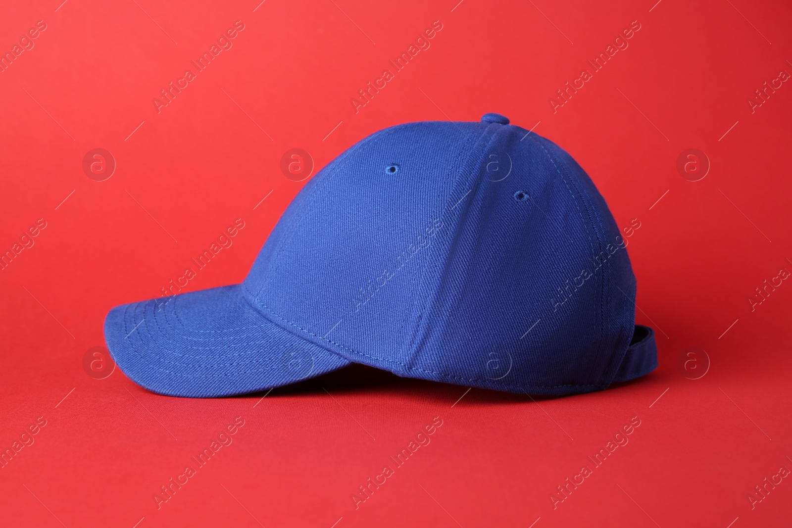 Photo of Stylish blue baseball cap on red background