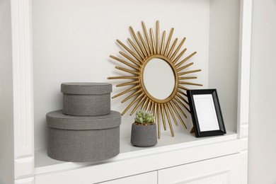 Photo of Grey decorative boxes, houseplant, mirror and frame on shelving unit