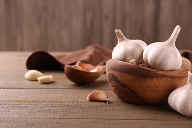 Photo of Fresh garlic on wooden table, closeup. Space for text