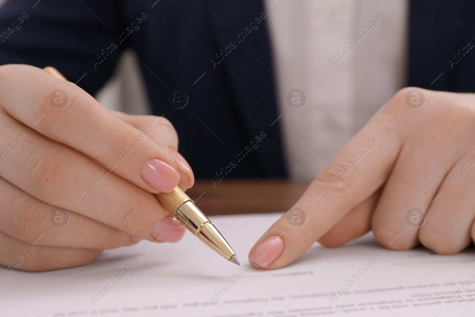 Photo of Woman signing document at table, closeup view