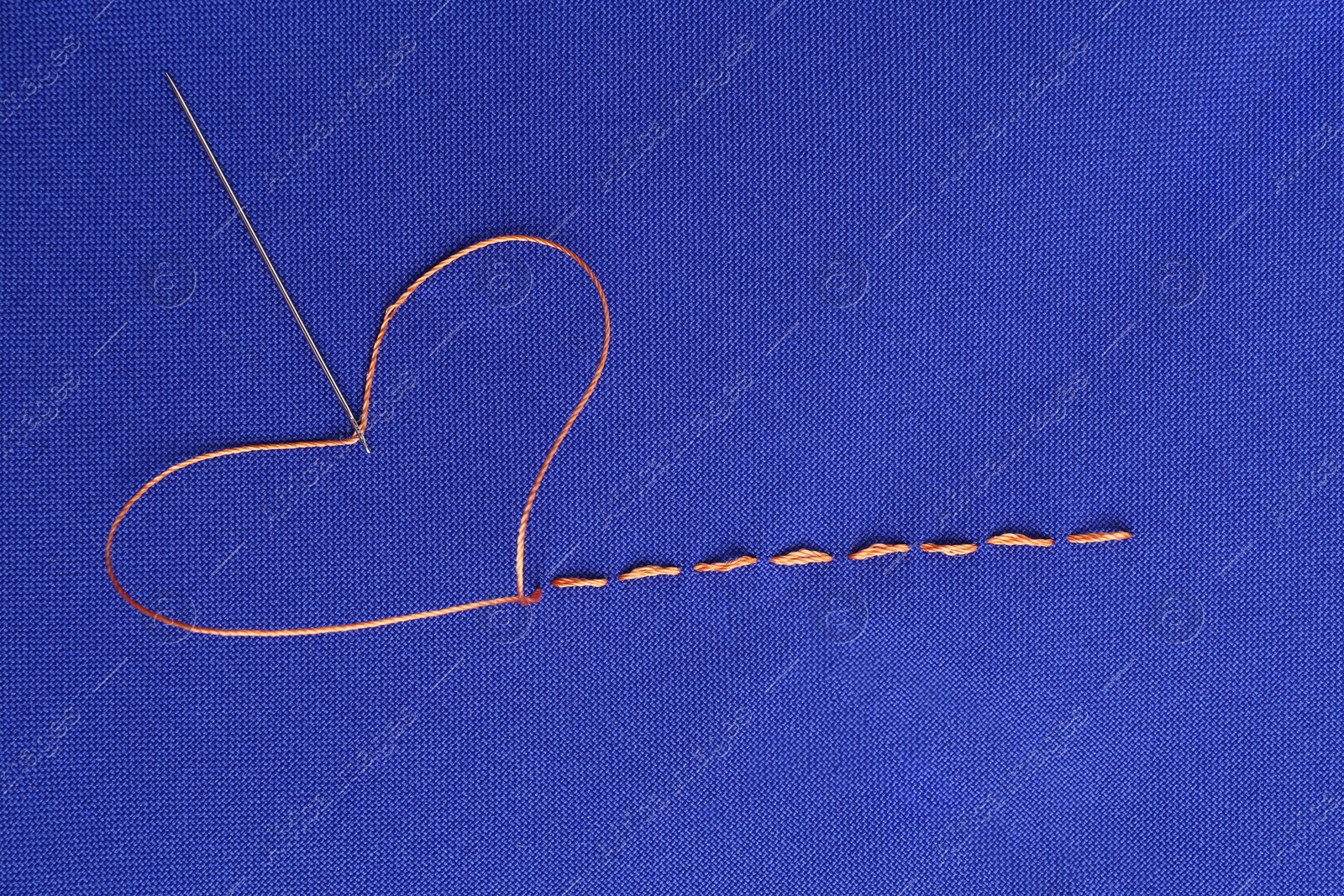 Photo of Sewing needle with thread and stitches on blue cloth, top view