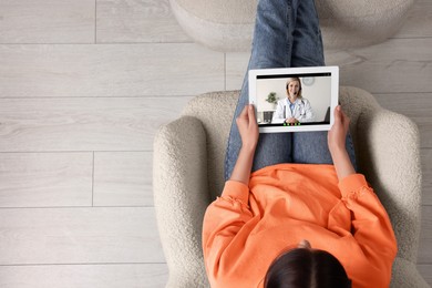 Image of Online medical consultation. Woman having video chat with doctor via tablet at home, top view. Space for text