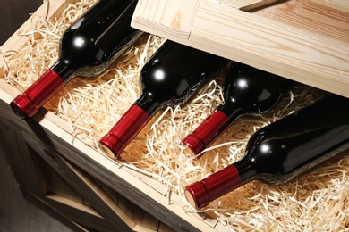 Photo of Wooden crate with bottles of wine, closeup