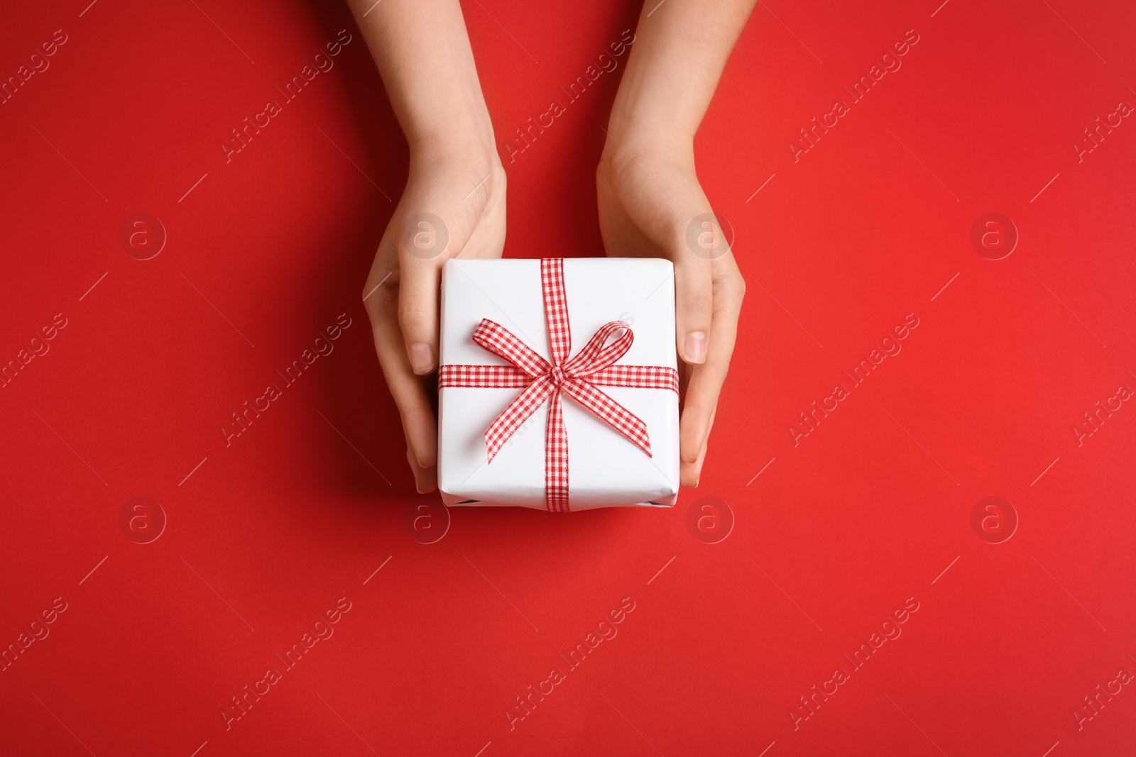 Photo of Woman holding gift box on color background, top view