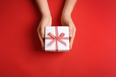 Photo of Woman holding gift box on color background, top view